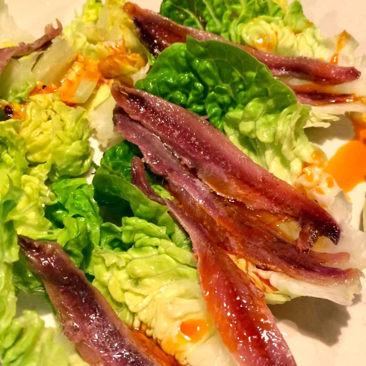 Gem Lettuce leaves topped with anchovies and chorizo juices